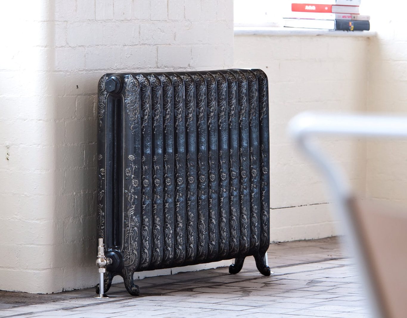 Black radiator against a wall in a minimalist, well-lit room.